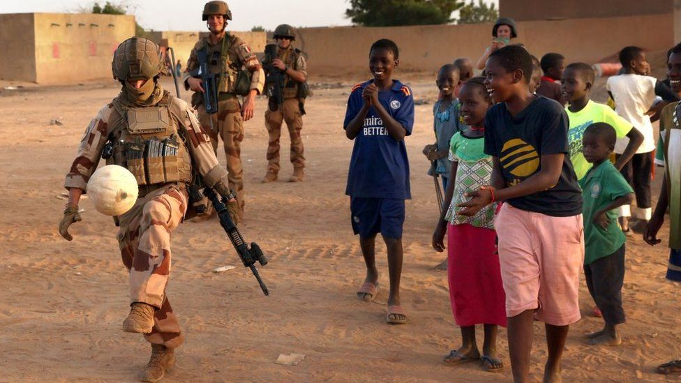 A French soldier plays football with a Malian child