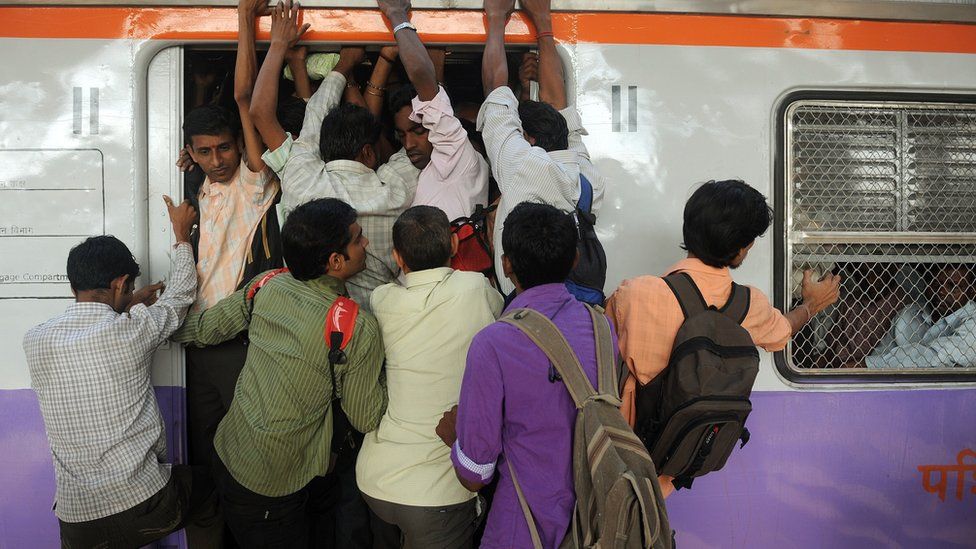 Commuters attempt to board a train in Mumbai
