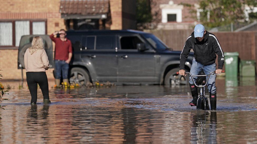 A man rides a bike through flooding in Retford in Nottinghamshire.