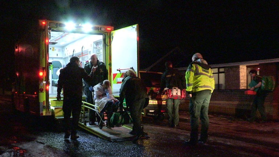 Patient being wheeled into an ambulance at night
