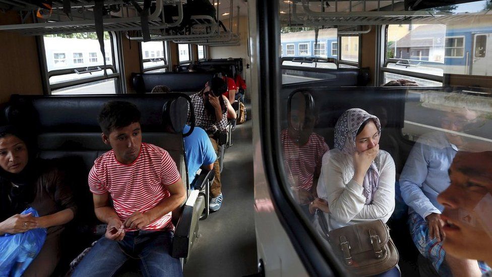 Asylum seekers wait on a train transporting them to a refugee camp