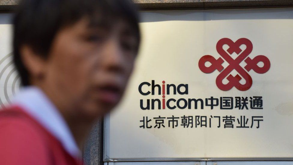 Man in soft focus in front of China Unicom sign.