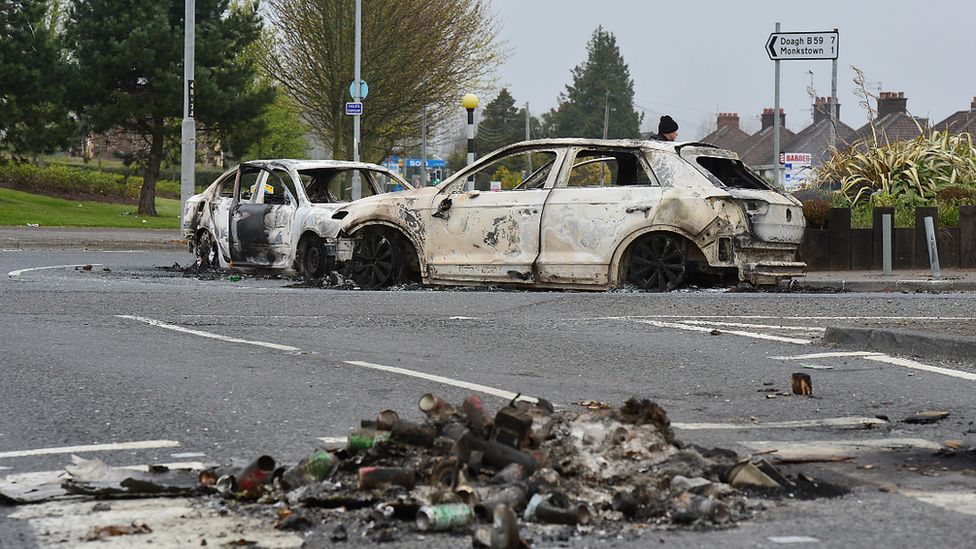 Burnt out cars remain on the road following violence in Newtownabbey