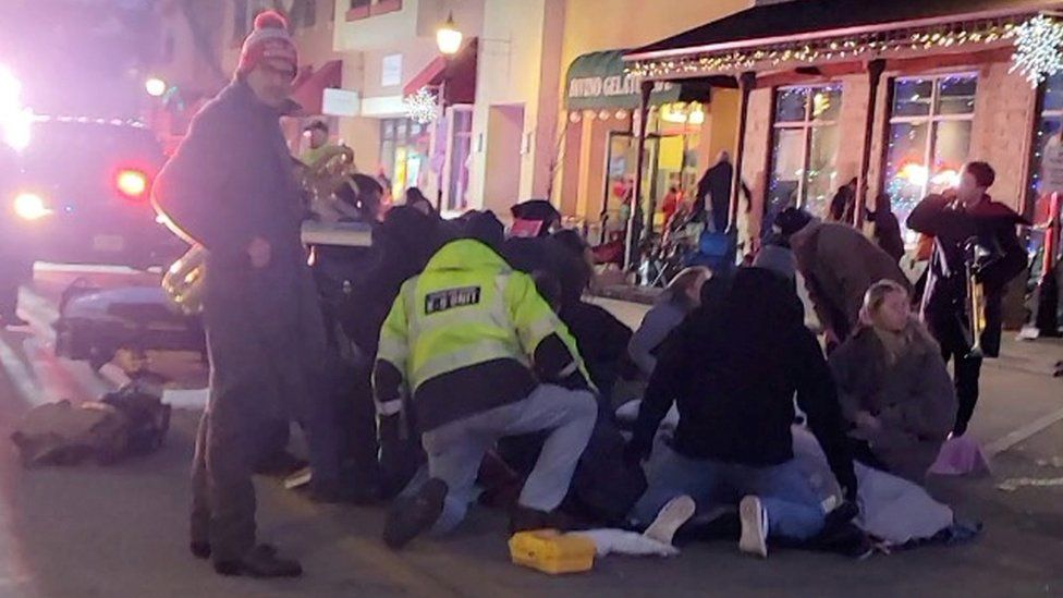 Emergency responders and passers-by attend to injured people after a vehicle plowed through a crowd at a Christmas parade, in Waukesha, Wisconsin, U.S., in this still image taken from a November 21, 2021 social media video.