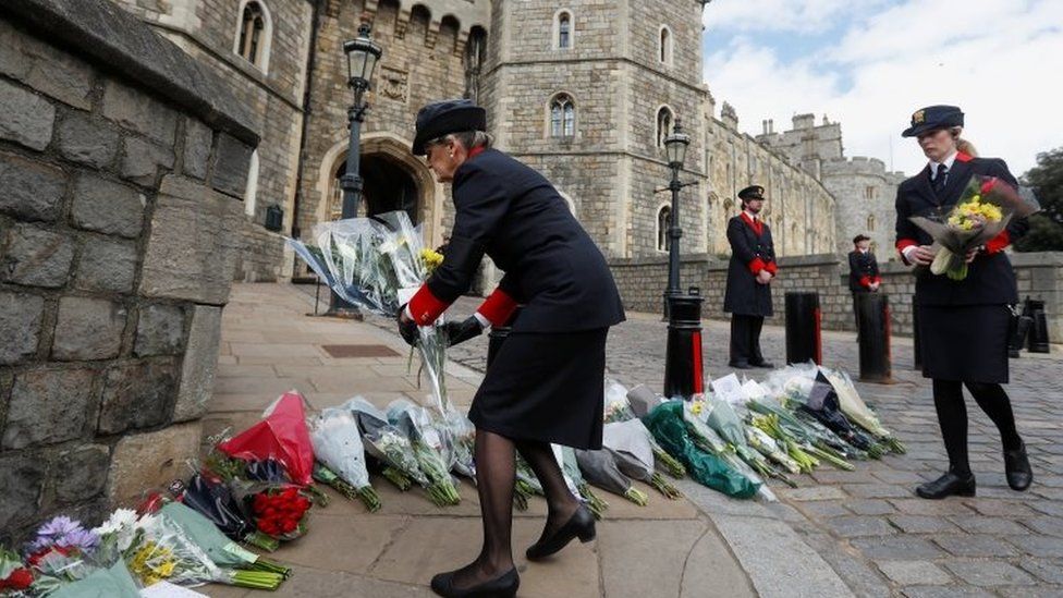 Windsor Castle wardens move flowers which were placed by members of the public outside Windsor Castle