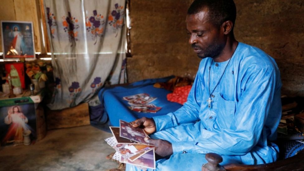 Benedict Ogbu looking at photos of his late wife Theresa Ogbu in their home in Owo, Nigeria - Tuesday 7 June 2022