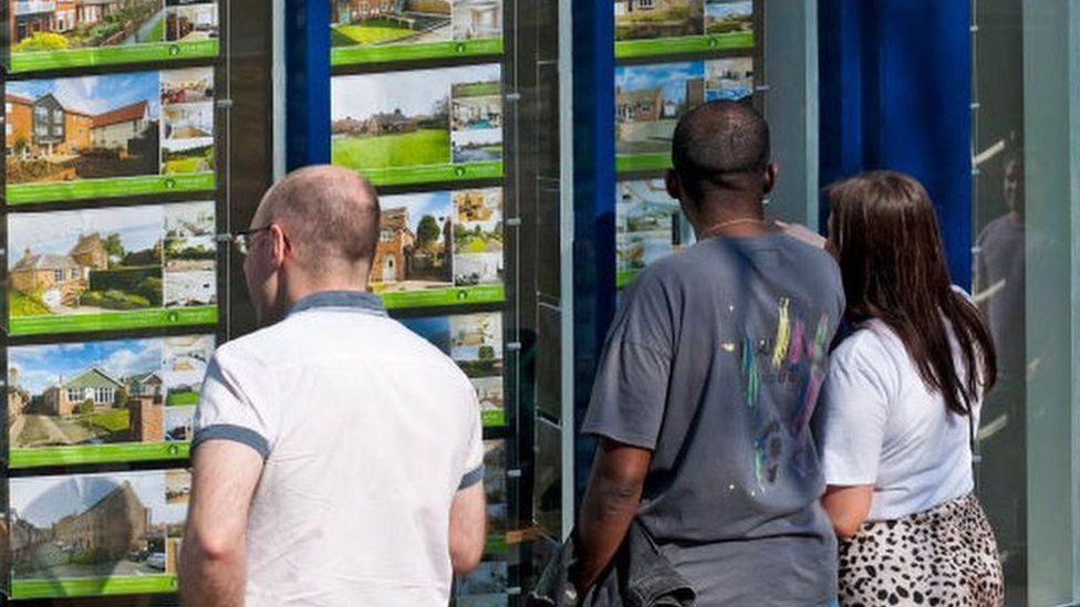 People looking in an estate agent's window.