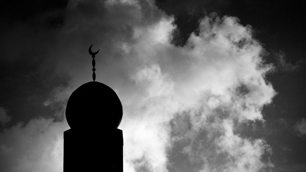 Minaret in silhouette against cloudy sky