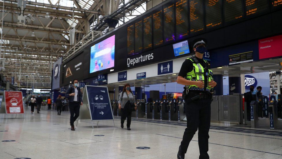 Police officer in face mask walks through empty Waterloo station