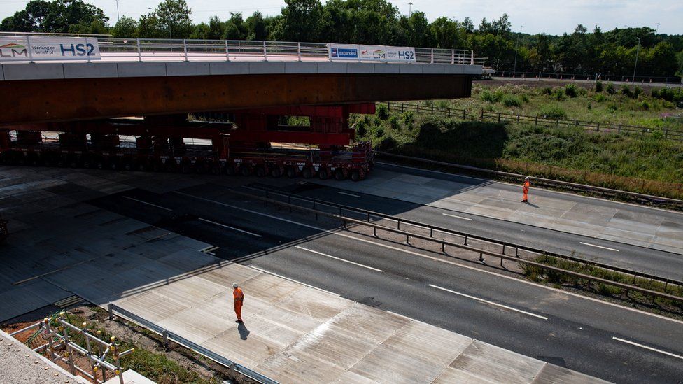 HS2 workers watch as a bridge is wheeled into position over the M42