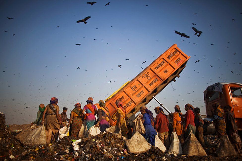 Indian workers called Rag Pickers, wait as a truck delivers garbage for them to sort through and pick out recyclable materials to sell from the 70 acre Ghazipur Landfill Site on February 18, 2010 in east Delhi,