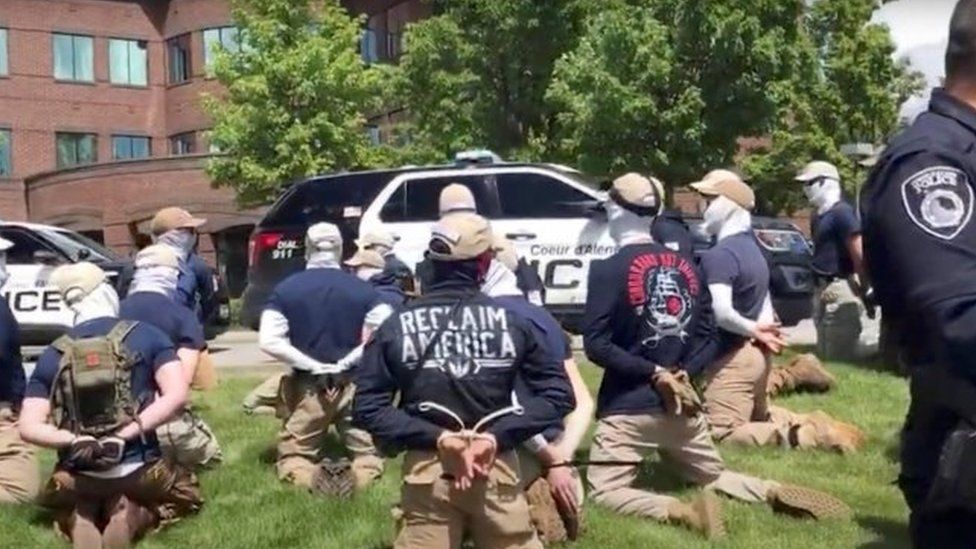 Suspected members of a white supremacist group guarded by police in Coeur D'Alene, Idaho. Photo: 11 June 2022