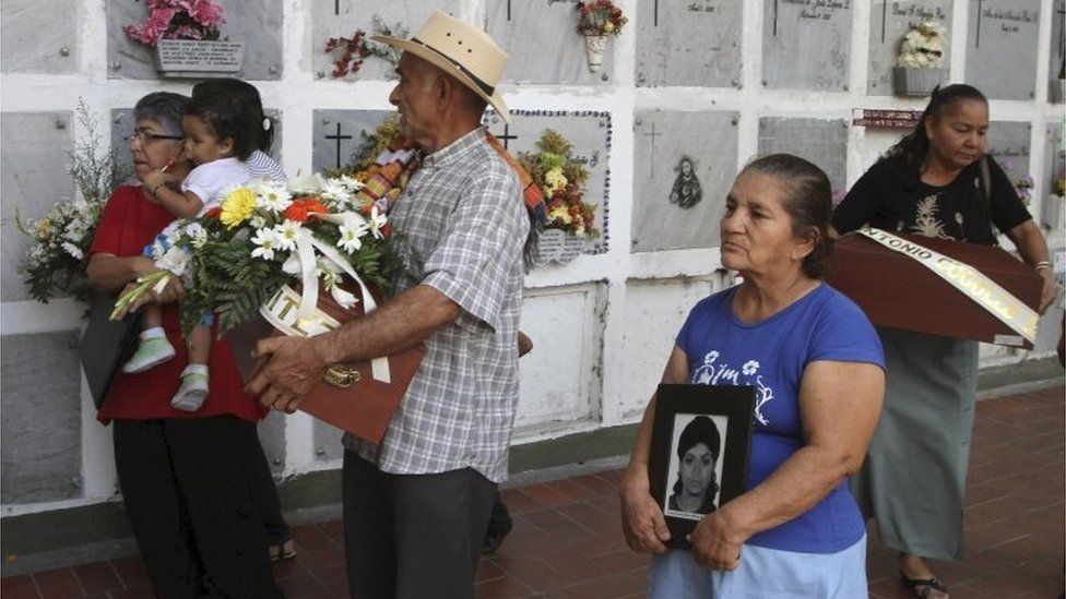Leonel de Jesus Vargas carries a small coffin containing the remains of his daughter Gloria, as he is accompanied by his wife Rosa, in San Pedro cemetery in Medellin on 25 February, 2011