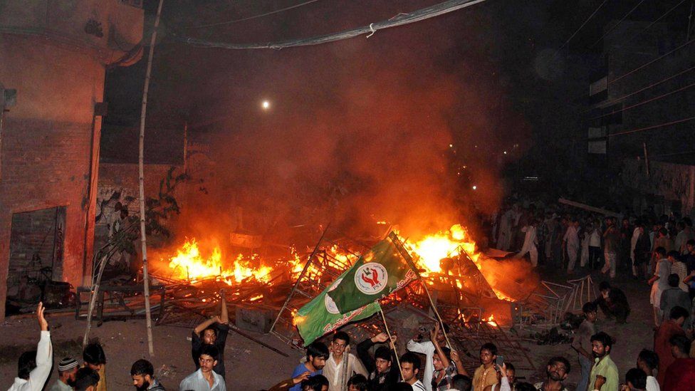 An angry mob after they set fire to household items belonging to a minority Ahmadi Muslim resident in the low-income Arafat Colony of the eastern city of Gujranwala, 27 July 2014