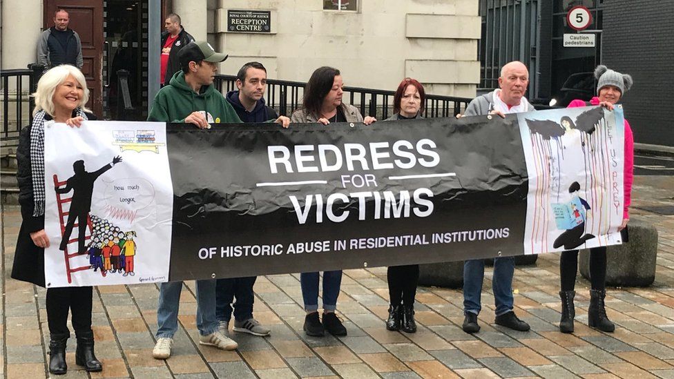 Victims campaigners hold a banner that reads: Redress for victims of historic abuse in residential institutions