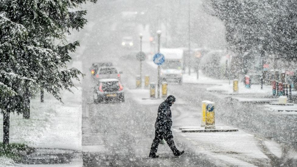 A man is seen crossing a road in heavy snow in Knaresborough, North Yorkshire.