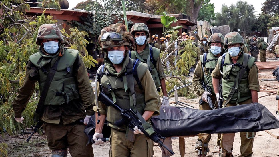 Israeli soldiers move bodies in Kfar Aza kibbutz