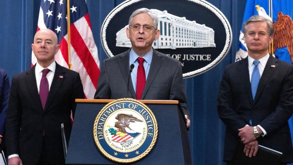 Merrick Garland stands with the Secretary of Homeland Security and the FBI Director.