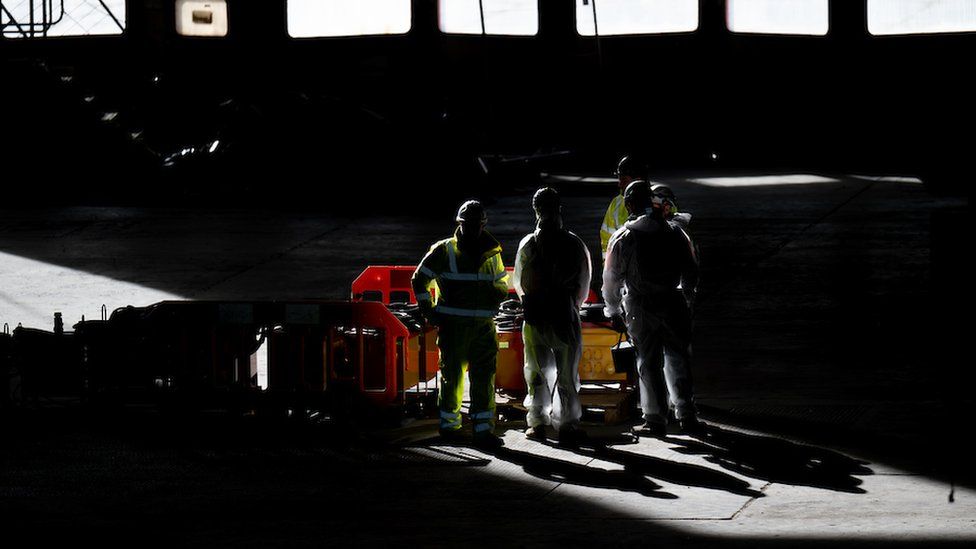 Workmen stand in a shaft of sunlight inside the Brabazon Hanger that will become Bristol's concert arena