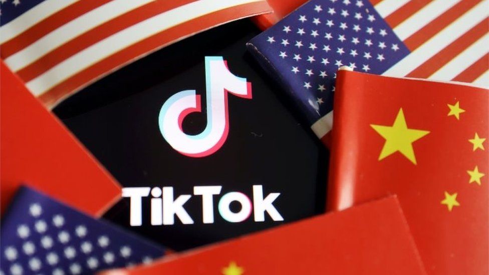 The TikTok logo is seen here partly covered by a ring of alternating US and Chinese flags