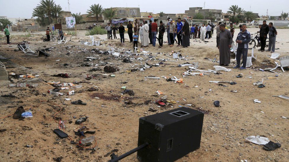 People inspect the aftermath of a suicide bombing at a soccer field in Iskandariya