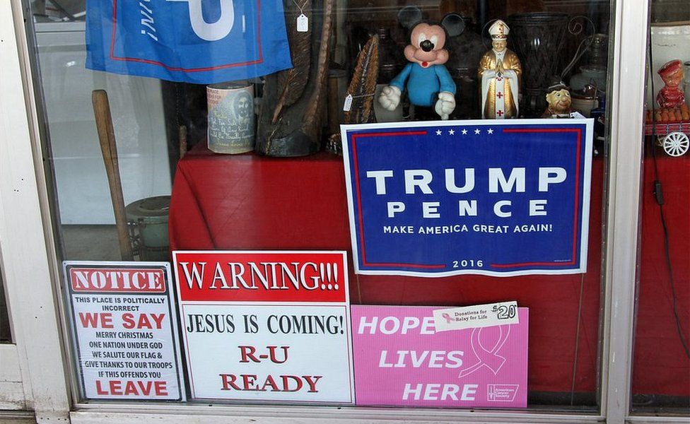 Shop window with Trump signs, a Mickey Mouse figure and an image of the Pope