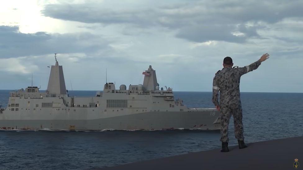 An Australian soldier waves to a US navy ship during a joint exercise in the Pacific