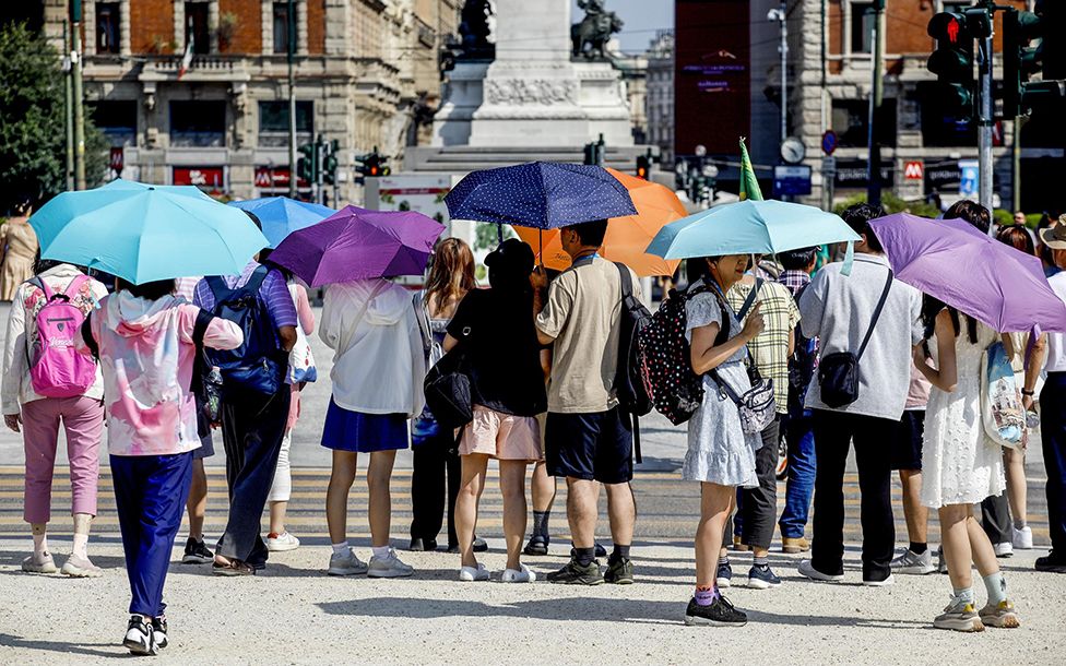People use umbrellas during a heat wave in Milan, Italy, 15 July