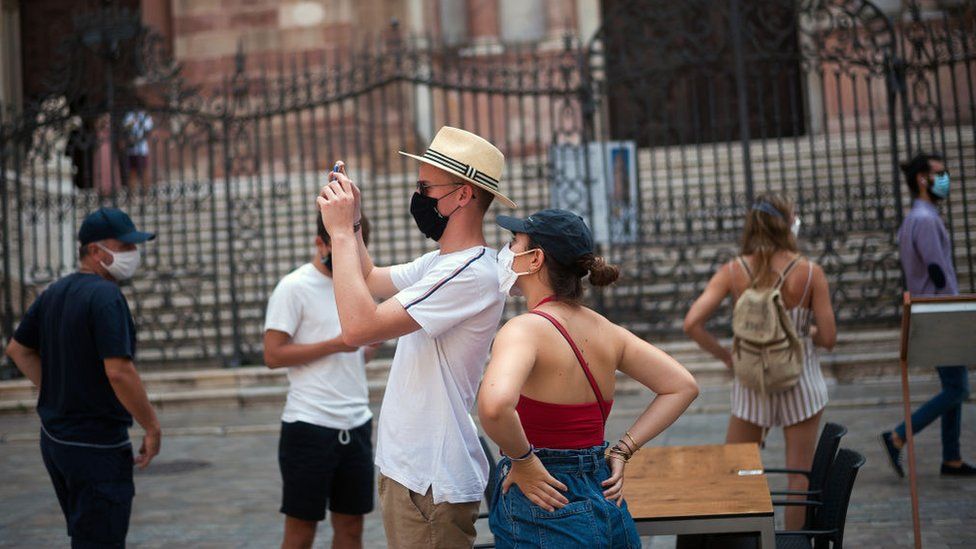 A tourist wearing a face mask takes photos at the Plaza del Obispo square in Malaga, Spain