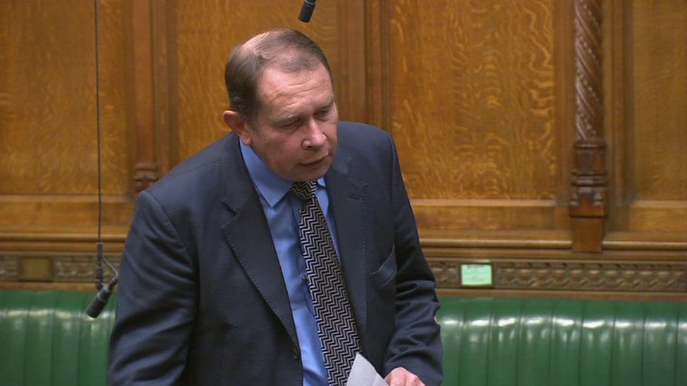 A man with short brown hair wearing a blue suit speaking in the House of Commons