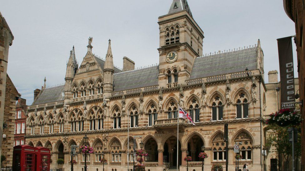 Victorian-Gothic three-storey stone building with flagpoles outside
