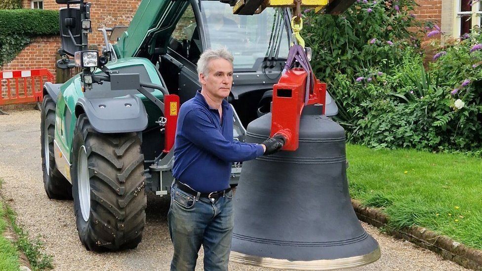 Matthew Boyd, fabric officer at the church, with a bell and a tractor