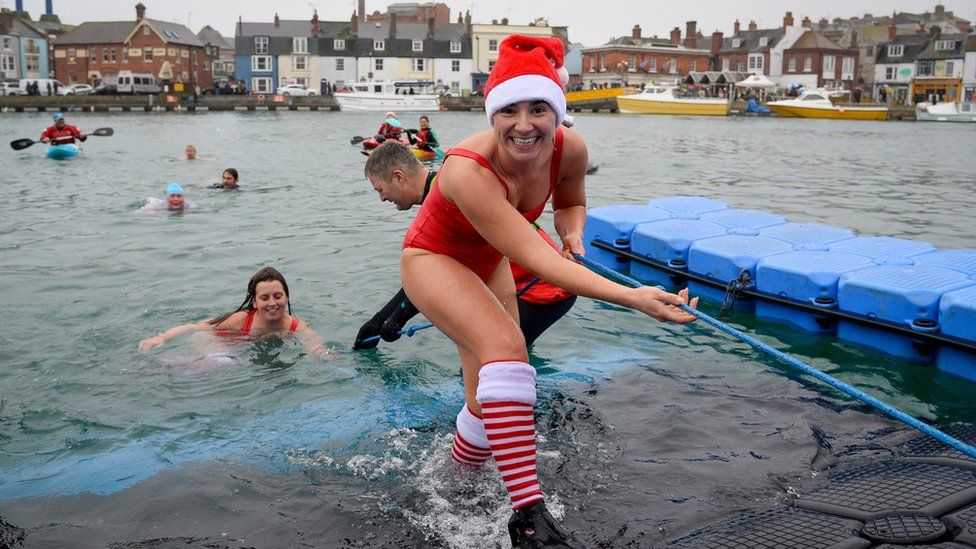 swimmers taking the plunge during the annual Christmas swim in Weymouth, Dorset, UK
