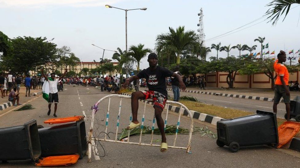 A protester sits on a barricade blocking a road in Lagos, Nigeria. Photo: 20 October 2020