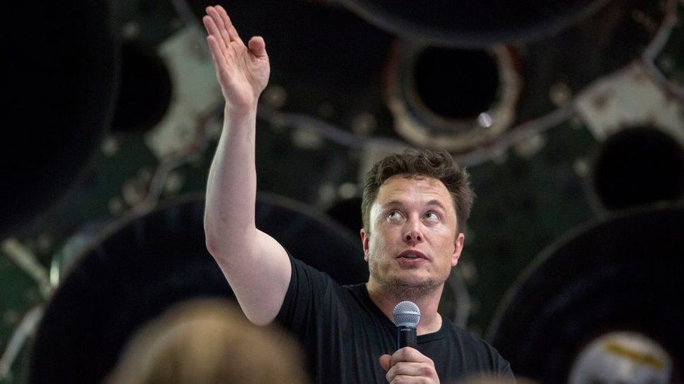 Elon Musk speaks near a Falcon 9 rocket