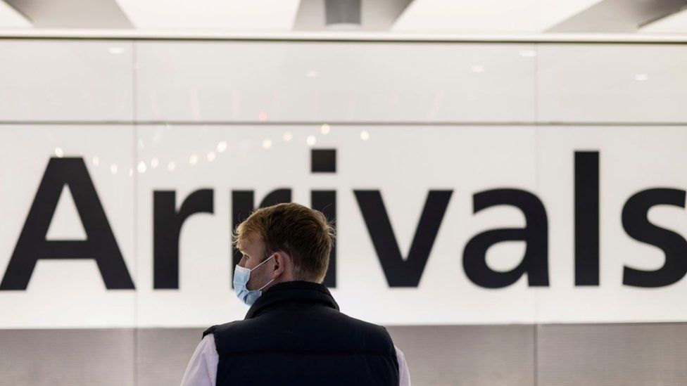 A man wearing a face mask is seen waiting at the arrival area of terminal 5, heathrow