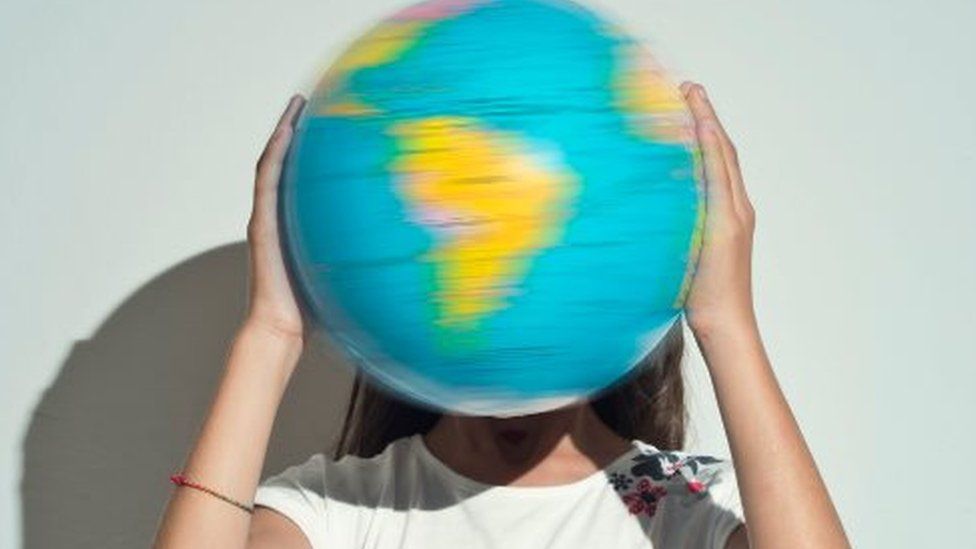 A girl holds a spinning globe