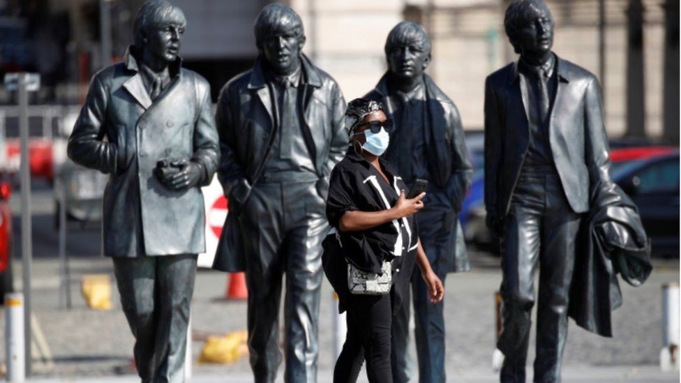 Beatles statue and woman wearing mask