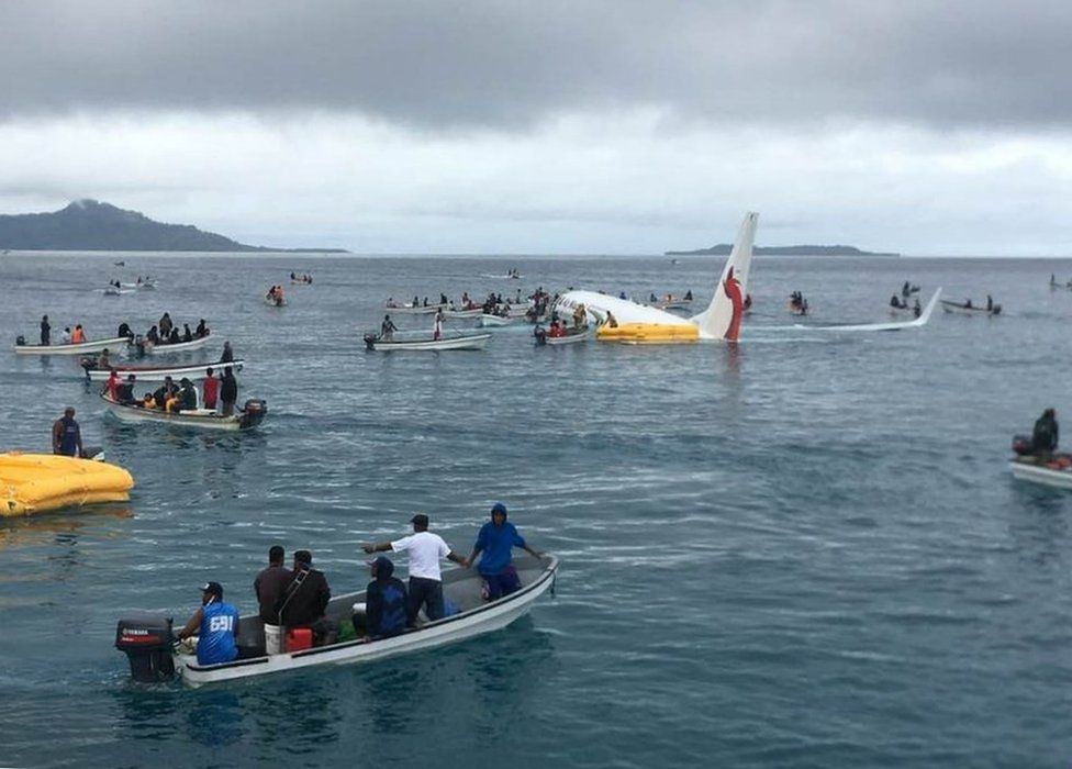 Small boats surround the Air Niugini plane in the water