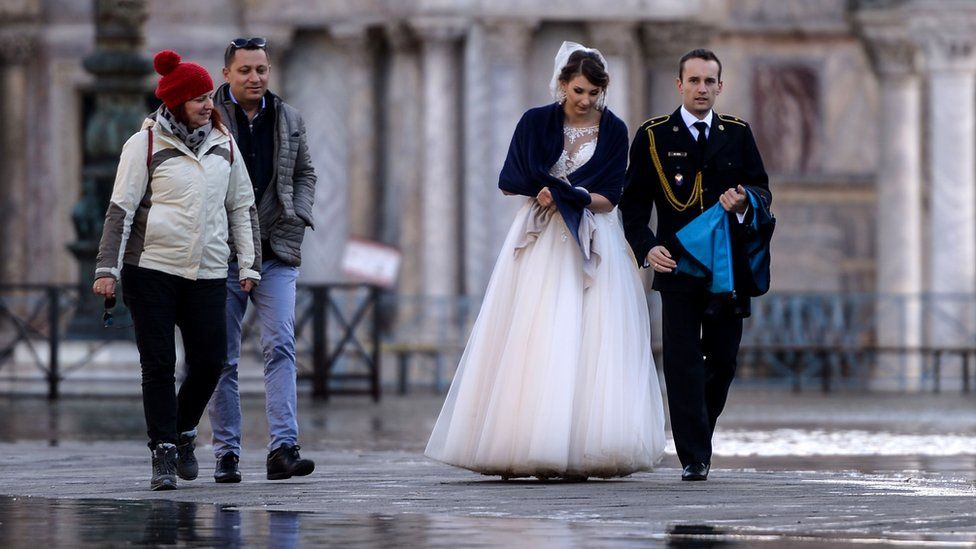 A newlywed couple walks across a flooded square in Venice, 14 November 2019