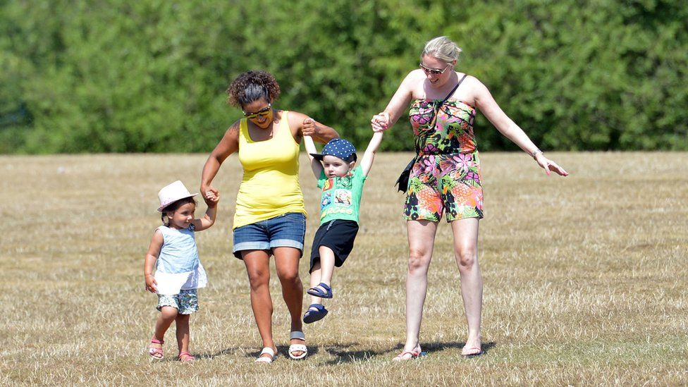Two women and two children in a park on a sunny day.