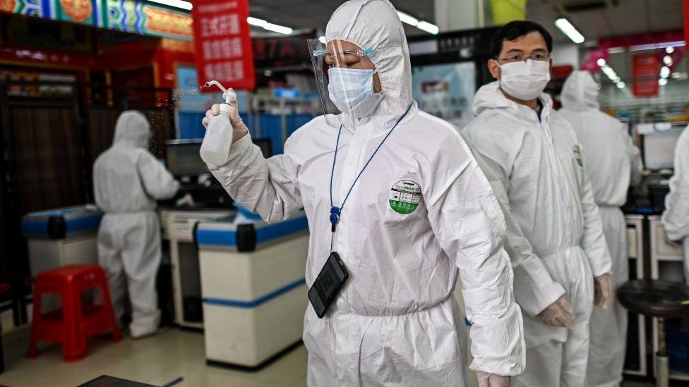 A woman wearing a protective suit sprays disinfectant in a pharmacy in Wuhan, in China's central Hubei province on March 30, 2020