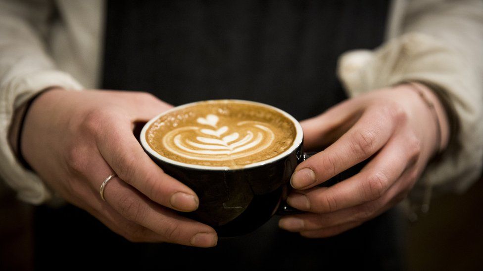 Barista holding cup of coffee