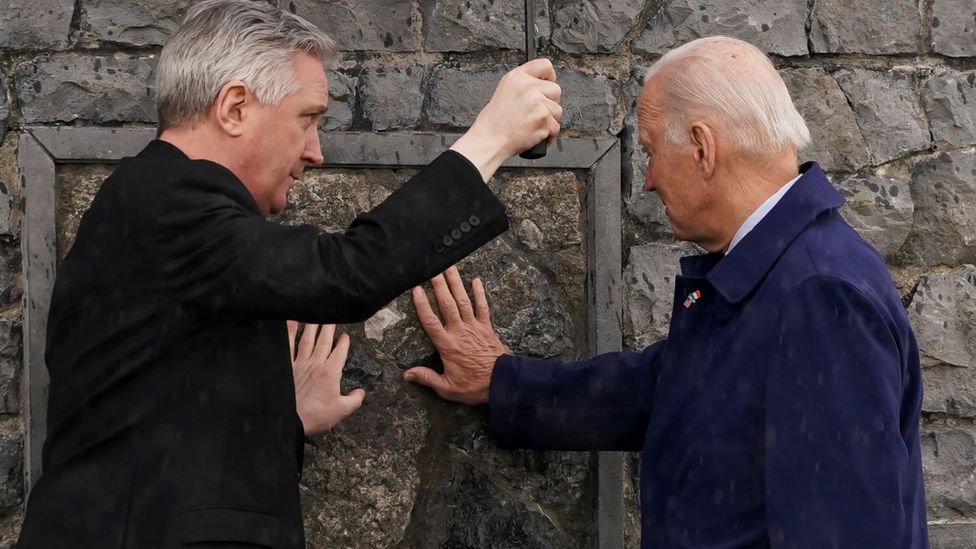 President Biden and Father Gibbons touch the original gable wall of the church at Knock Shrine