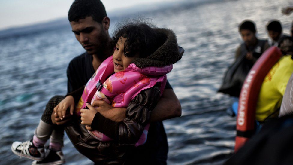 A migrant holding his child arrives with other refugees on the Greek island of Lesbos. 7 October 2015