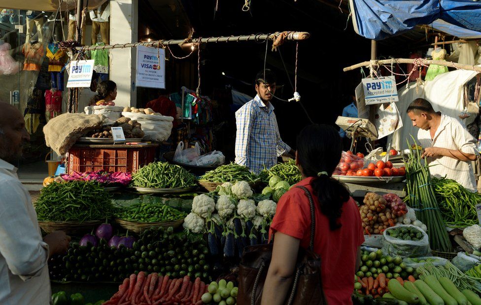 A sign advertising Indian mobile payments from Paytm hangs at vegetable stalls in Mumbai.
