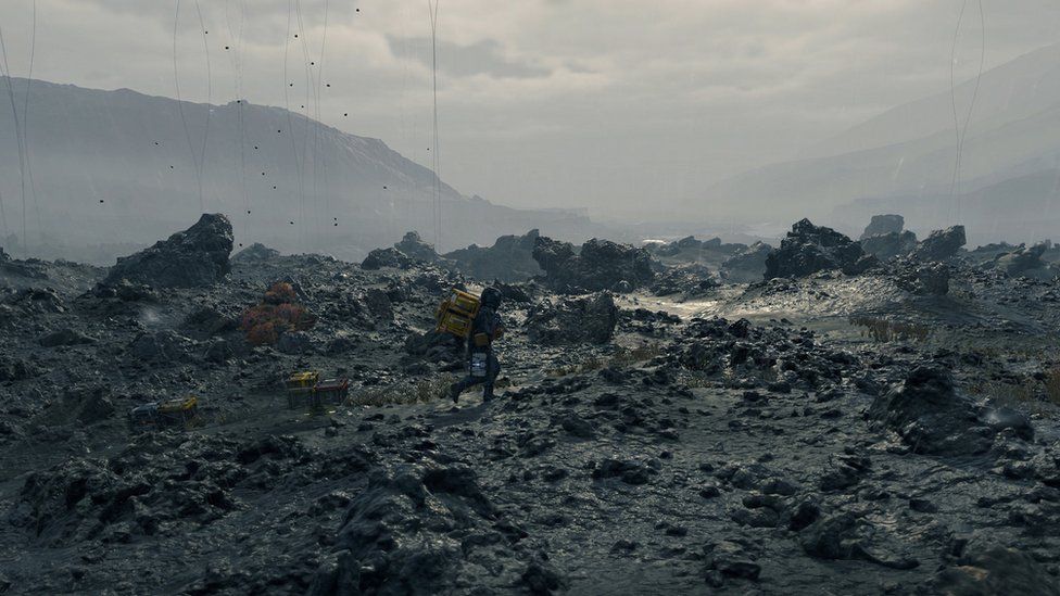 A man drags a futuristic looking package across a barren, rocky landscape.