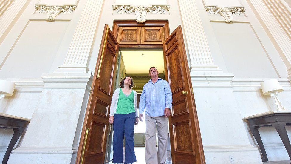 Two people walking through door