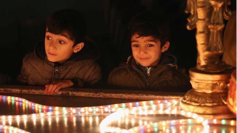 Young boys look at a light installation as people gather to celebrate the Hindu festival of Diwali