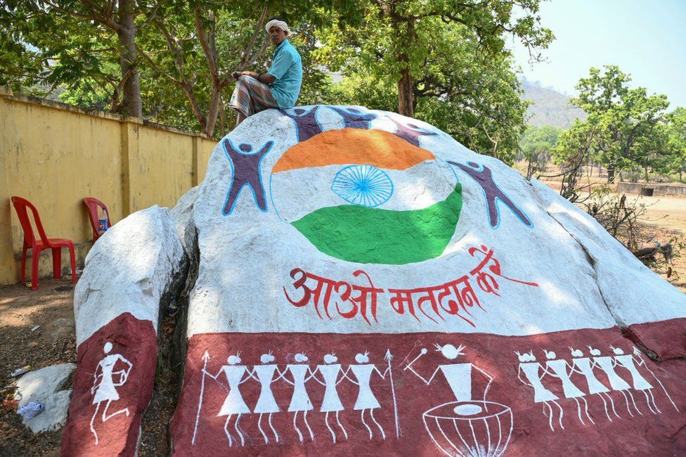 A voter sits on a boulder painted with voter awareness mural,while waiting outside a polling station to cast his ballot during the first phase of voting for the India's general election, in Dugeli village of Dantewada district of Chhattisgarh state on April 19, 2024
